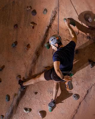 Person scaling indoor rock climbing wall